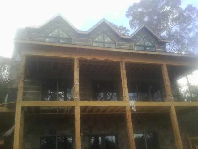 Dormers and porch framing on a large log home under construction — Roof Coating work by our crew in Granite