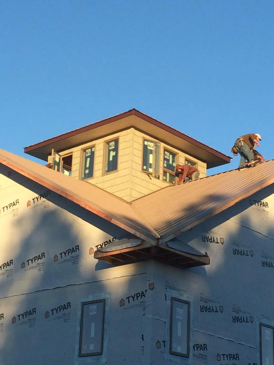 Roofers working around a rooftop cupola on a new metal roof at sunset — Roof Waterproofing in Granite by Roofing Brothers
